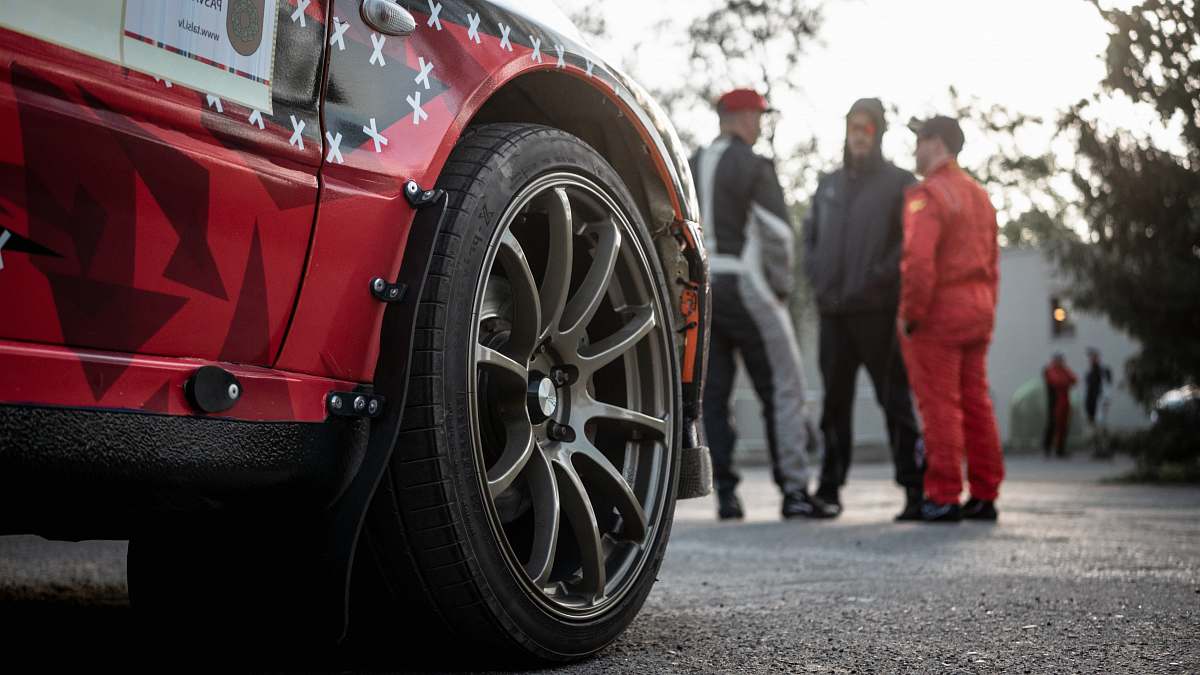 person three men standing in front of red car people