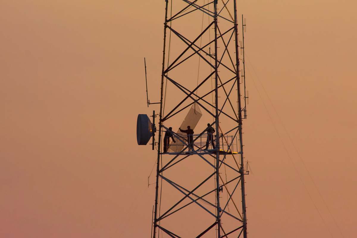 person three people standing on crane tower cable