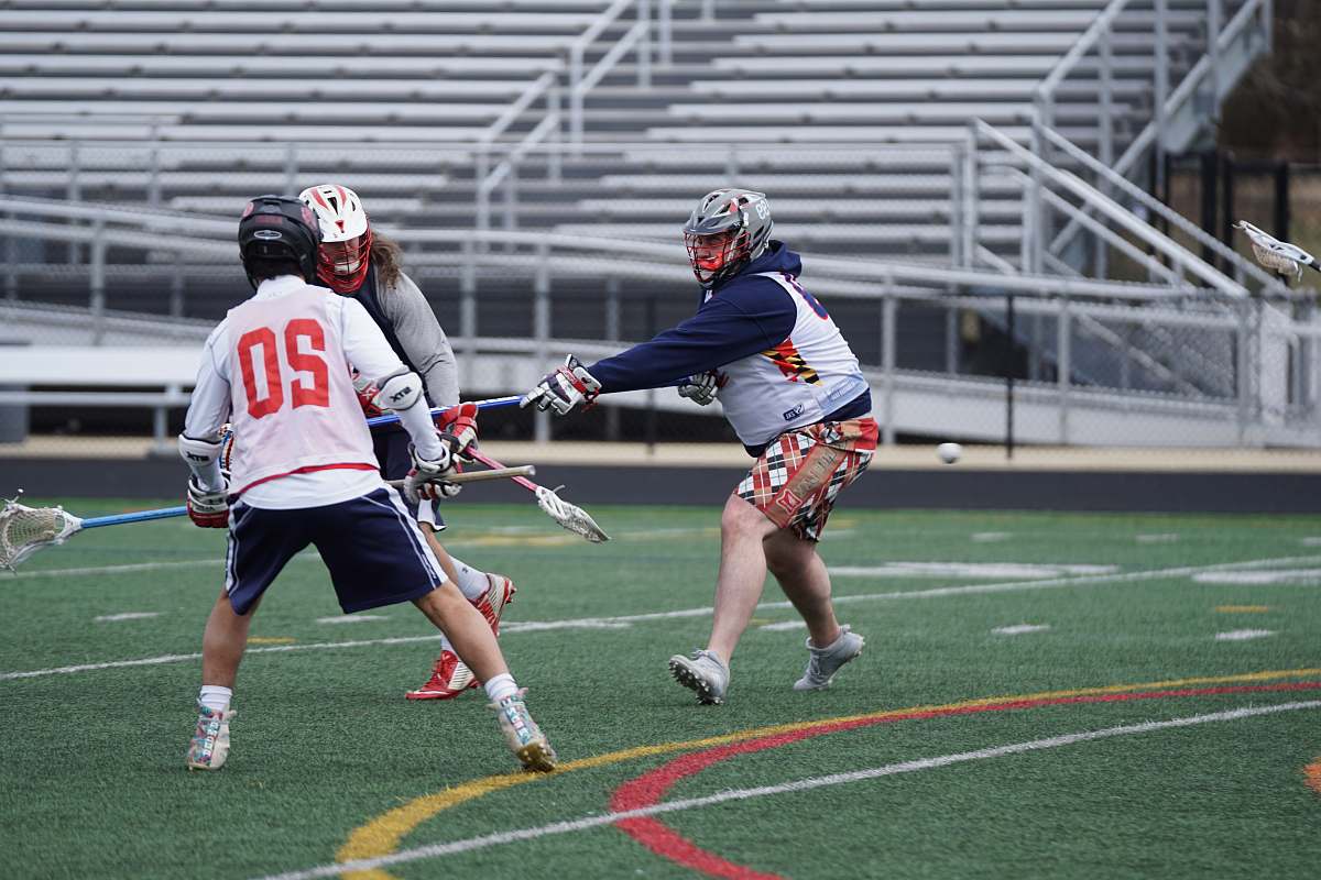 apparel three person playing lacrosse on field during daytime clothing