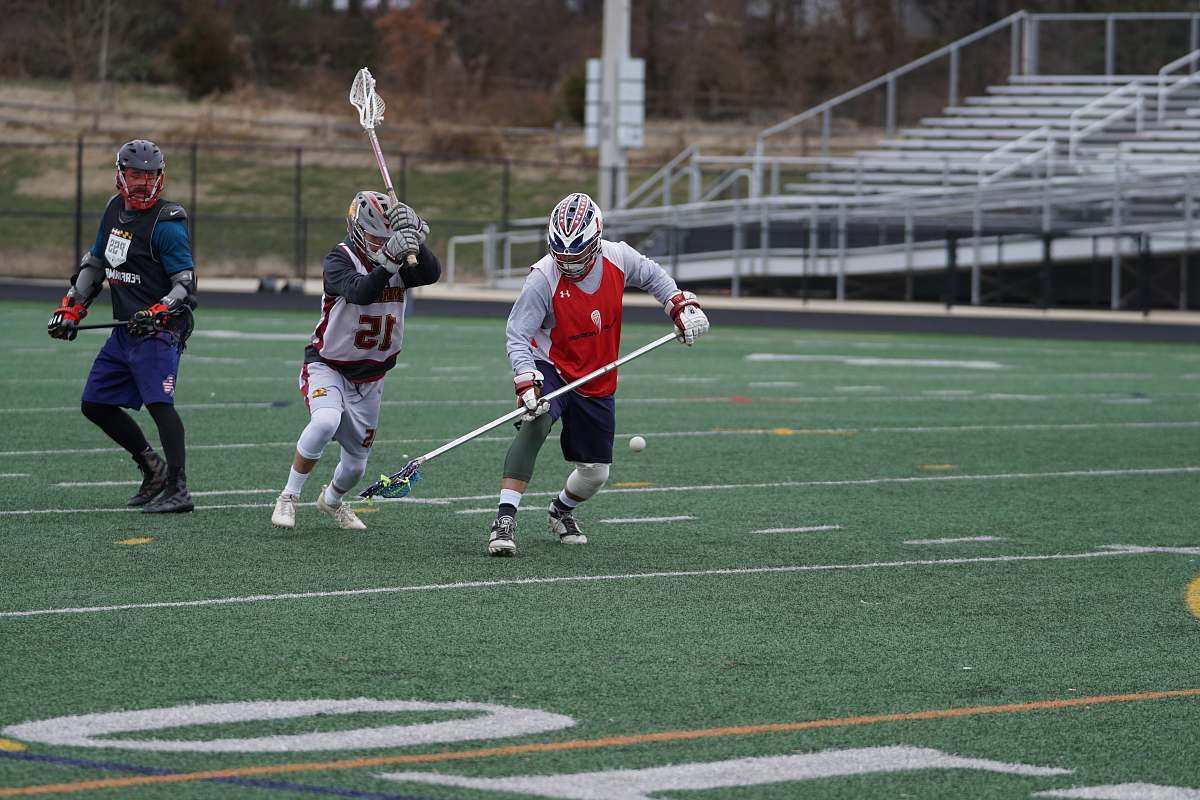 person three person playing lacrosse on field during daytime people