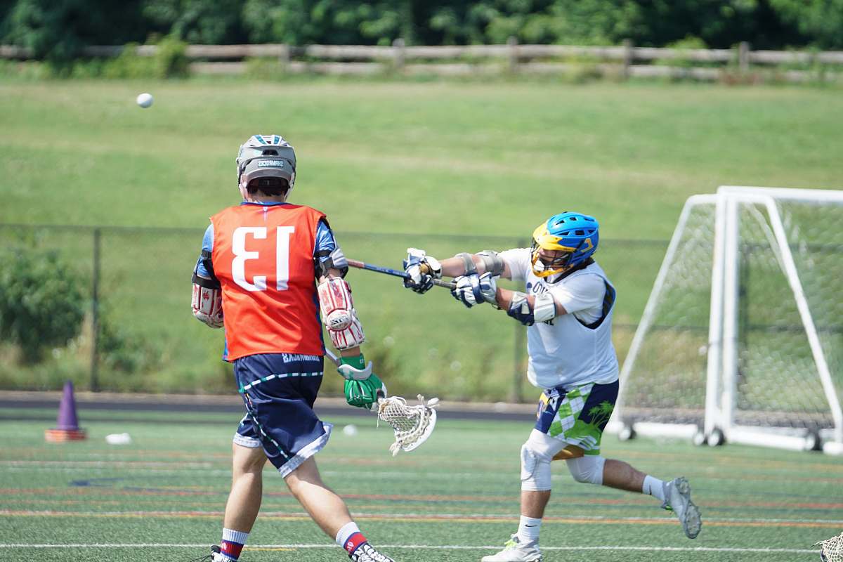 person two men playing lacrosse during daytime apparel