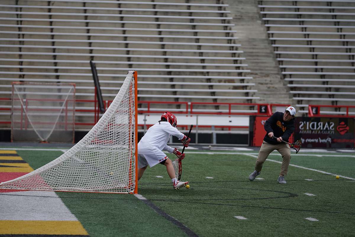 person two men playing lacrosse outside people