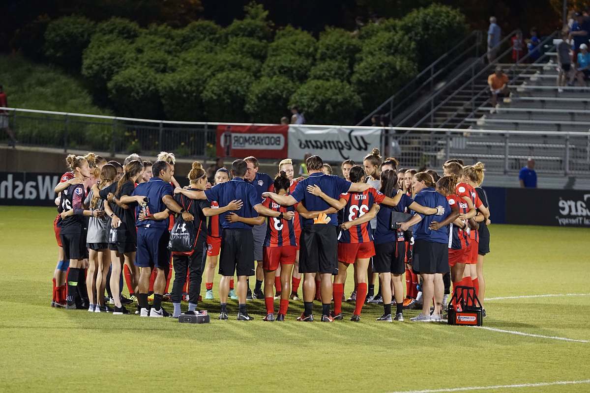 people two soccer teams on green field huddle