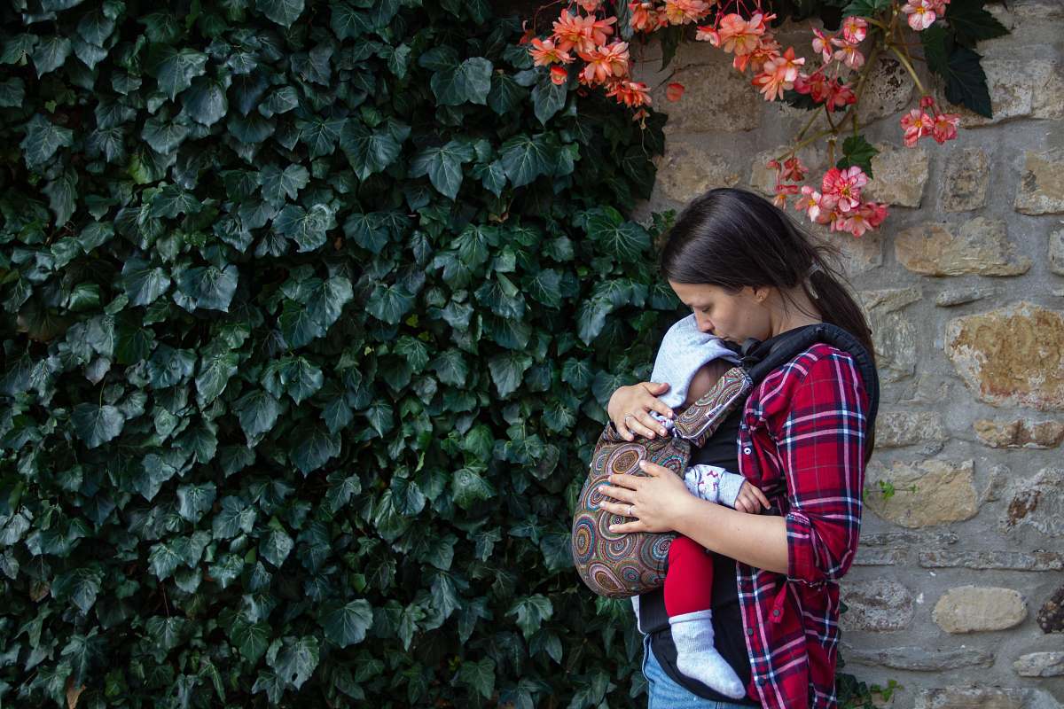apparel woman carrying baby near hedge clothing