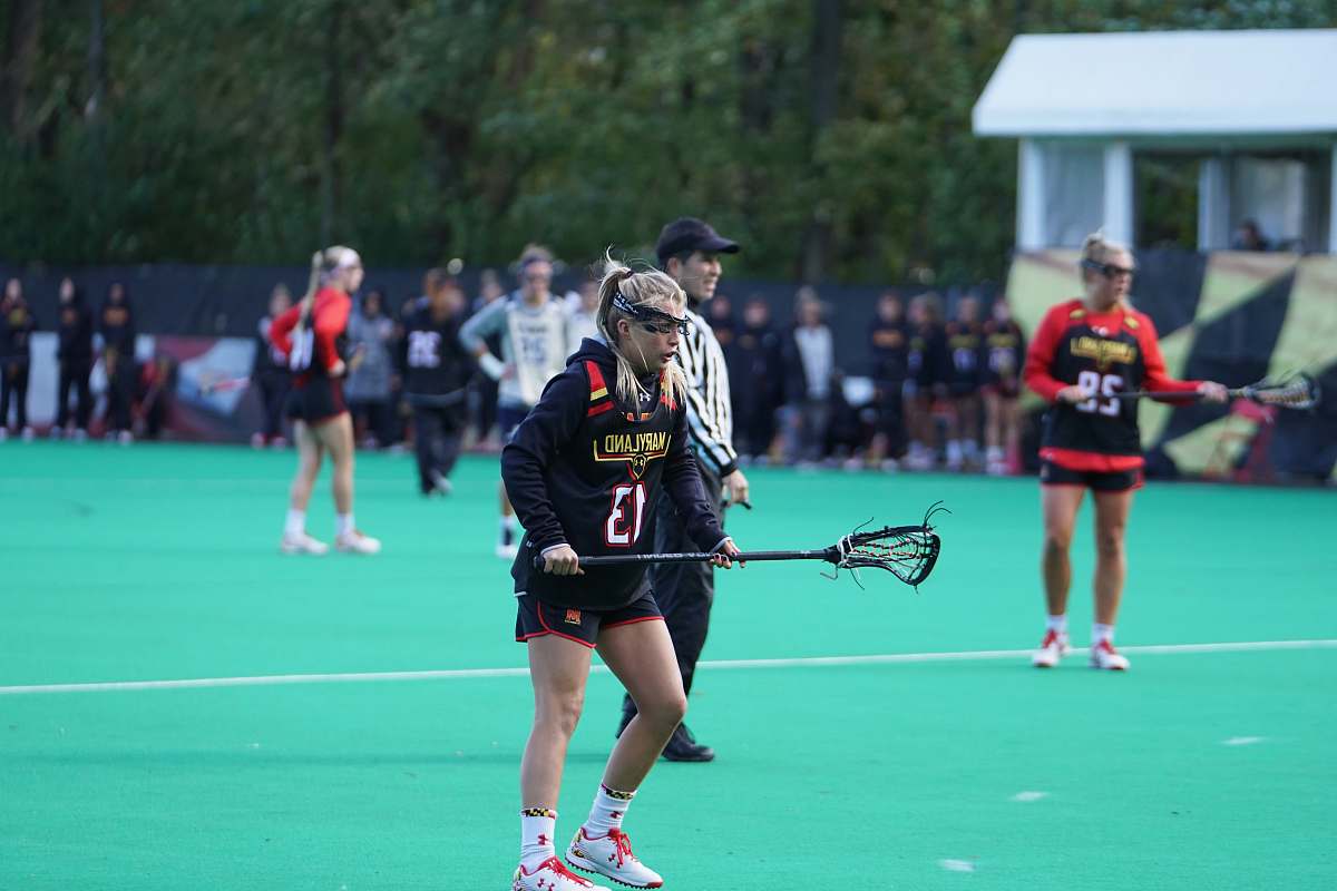 person woman holding black lacrosse stick apparel