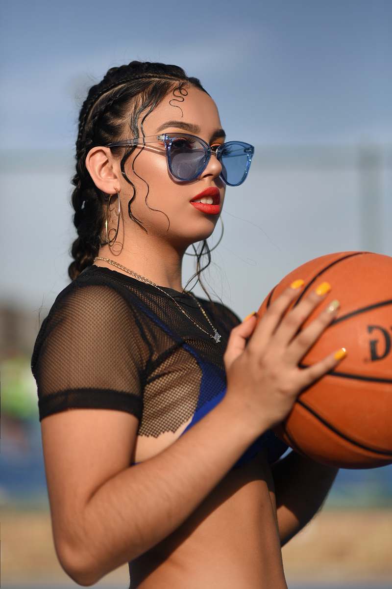 person woman in black mesh crop top holding basketball accessories