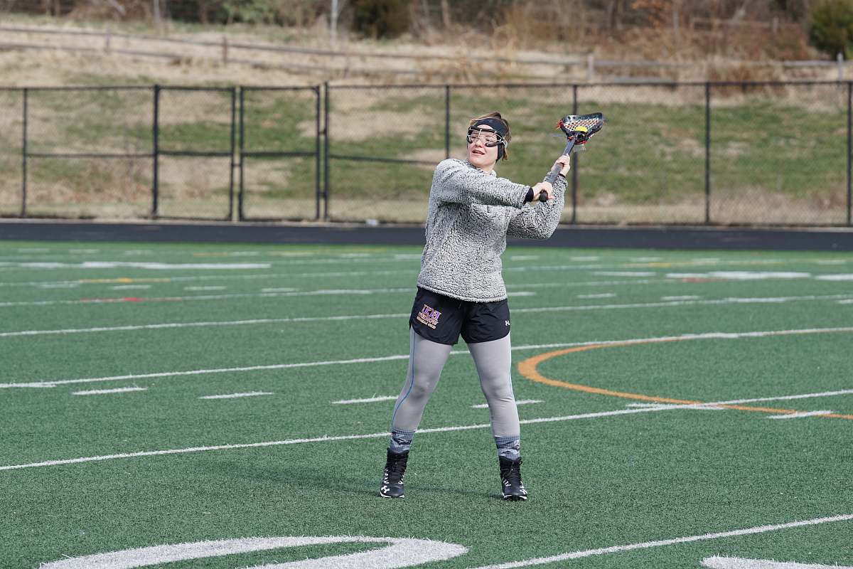person woman in grey sweat shirt playing lacrosse during daytime people