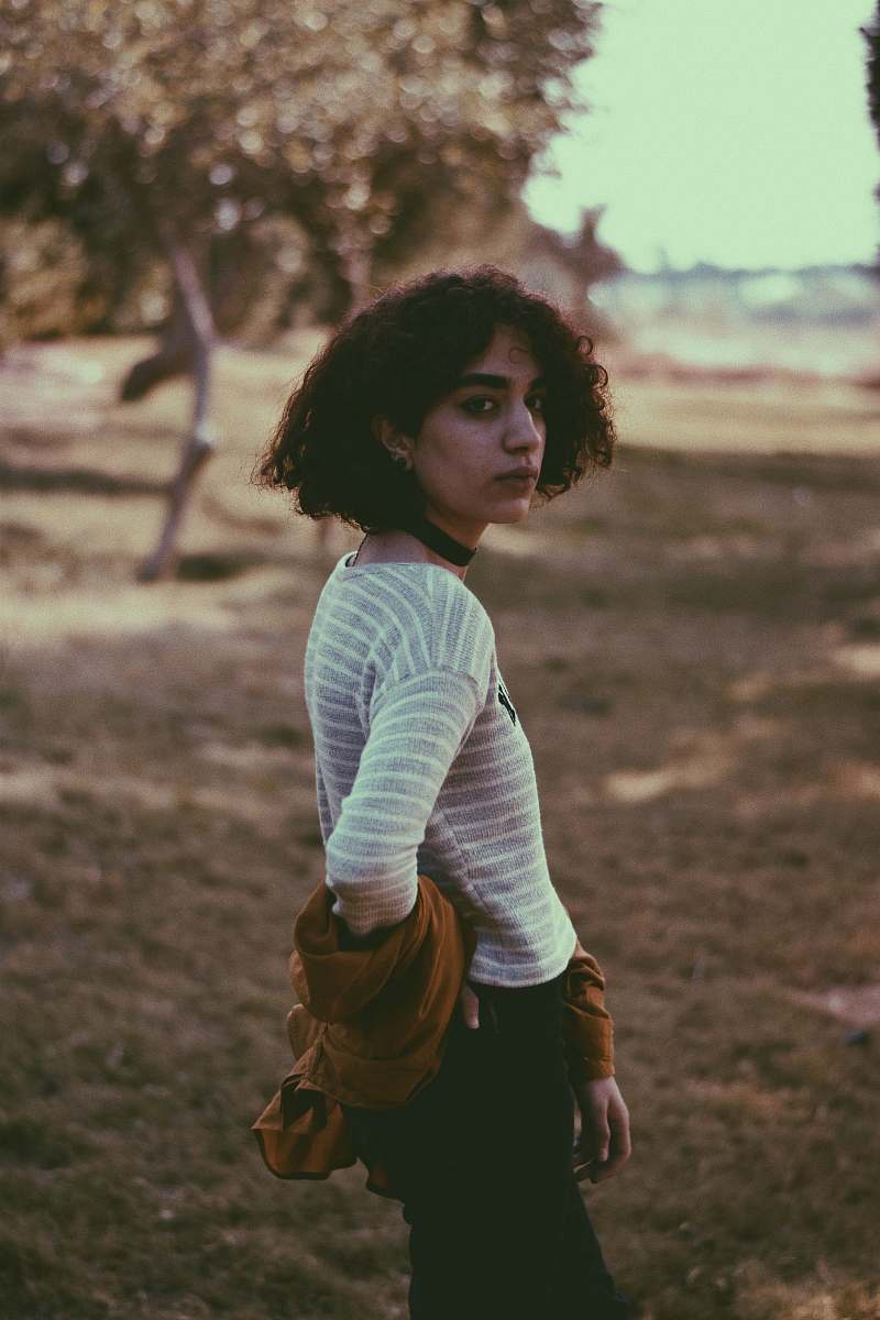 hair woman in white shirt standing near green trees afro hairstyle