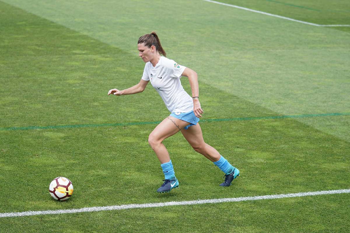 person woman on football field dribbling soccer ball at daytime people