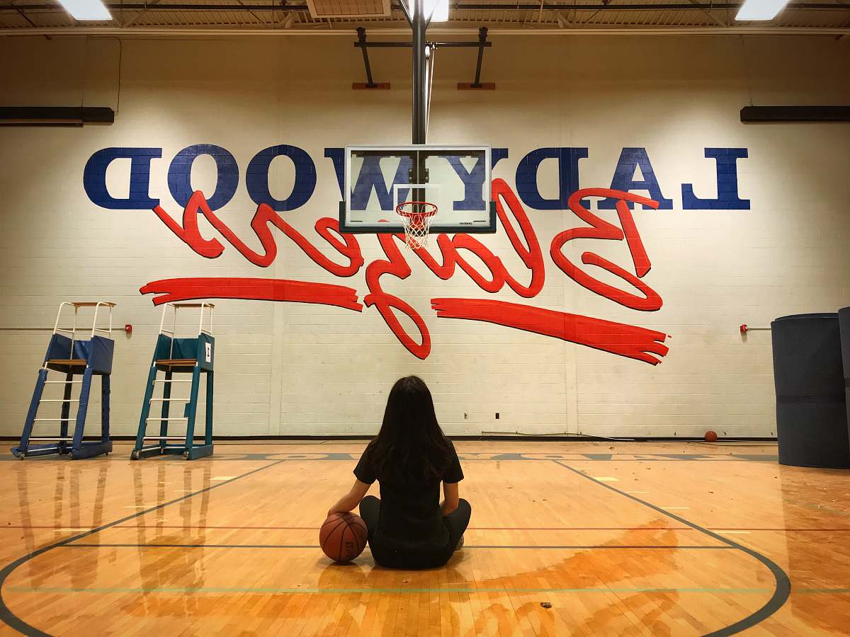 person woman sitting in basketball court floor people
