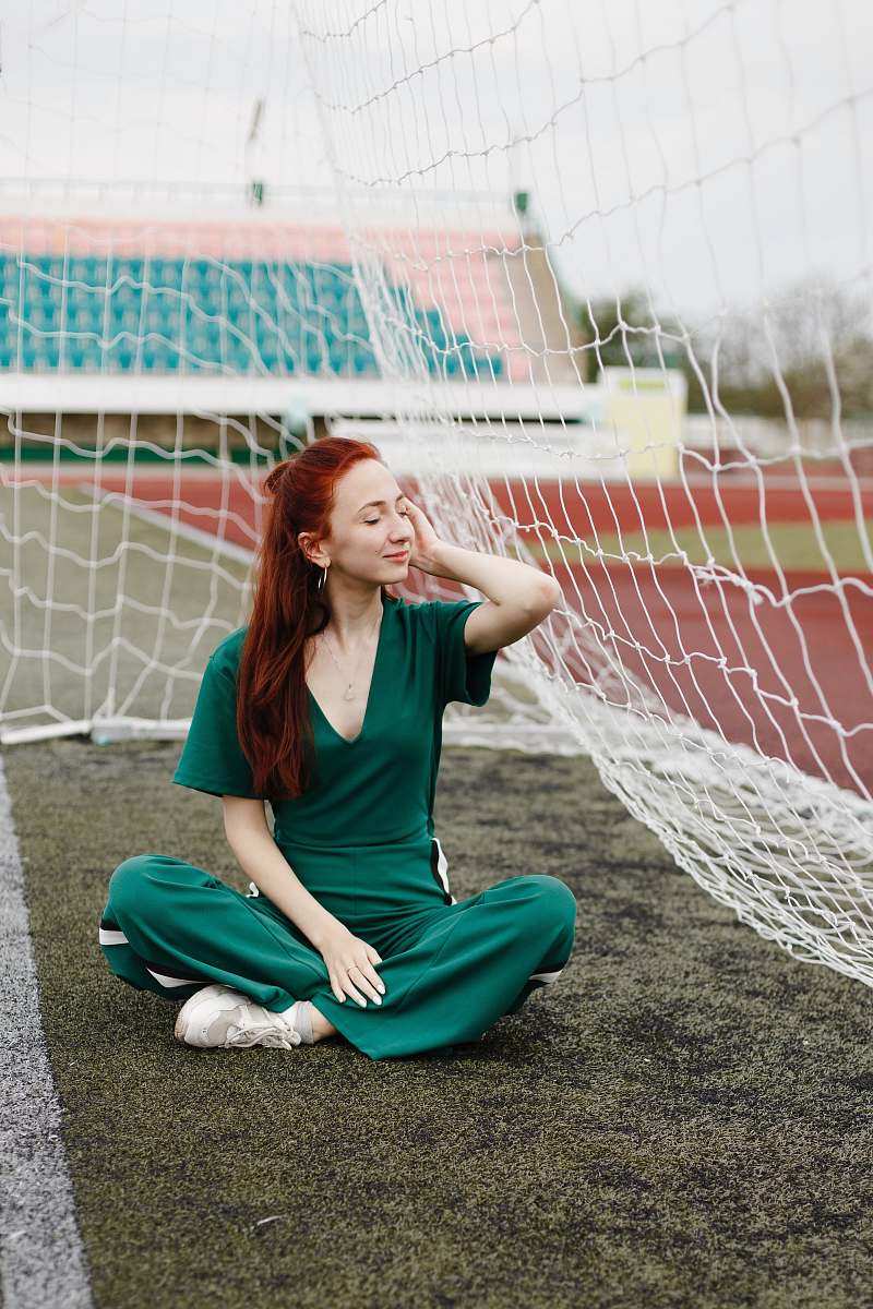 person woman sitting in green overalls beside net sphere