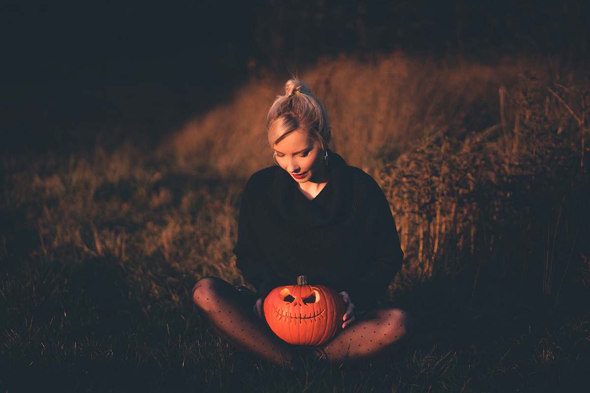 person woman wearing black hoodie holding jack o lantern bucket sphere