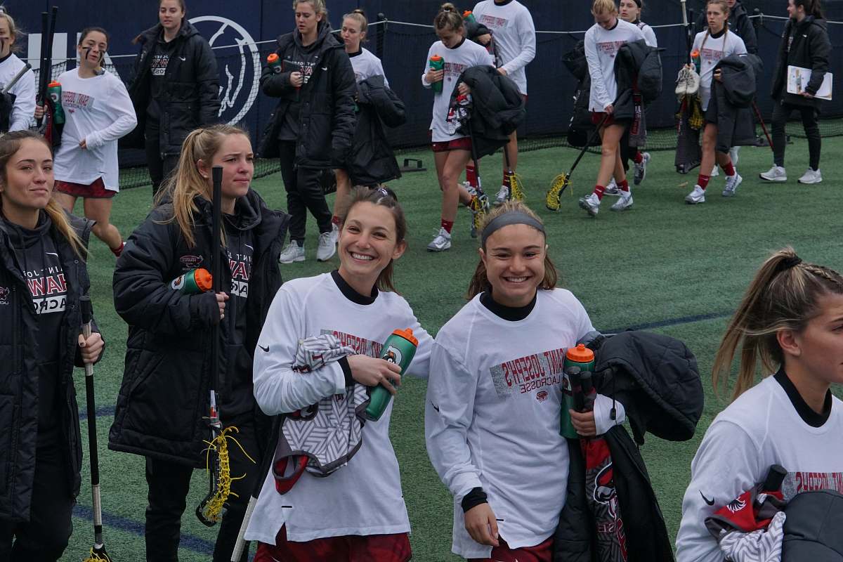 person women holding lacrosse sticks on green field people