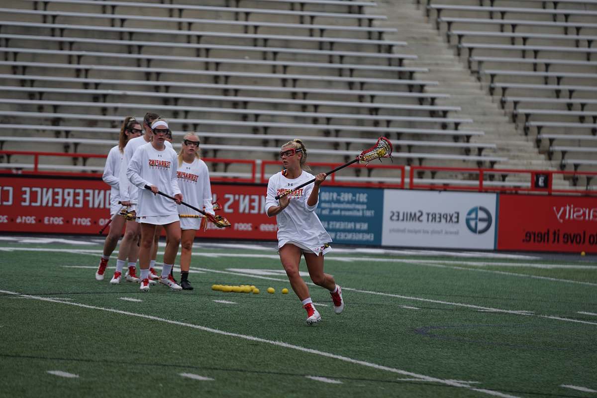 person women on field playing lacrosse during daytime field