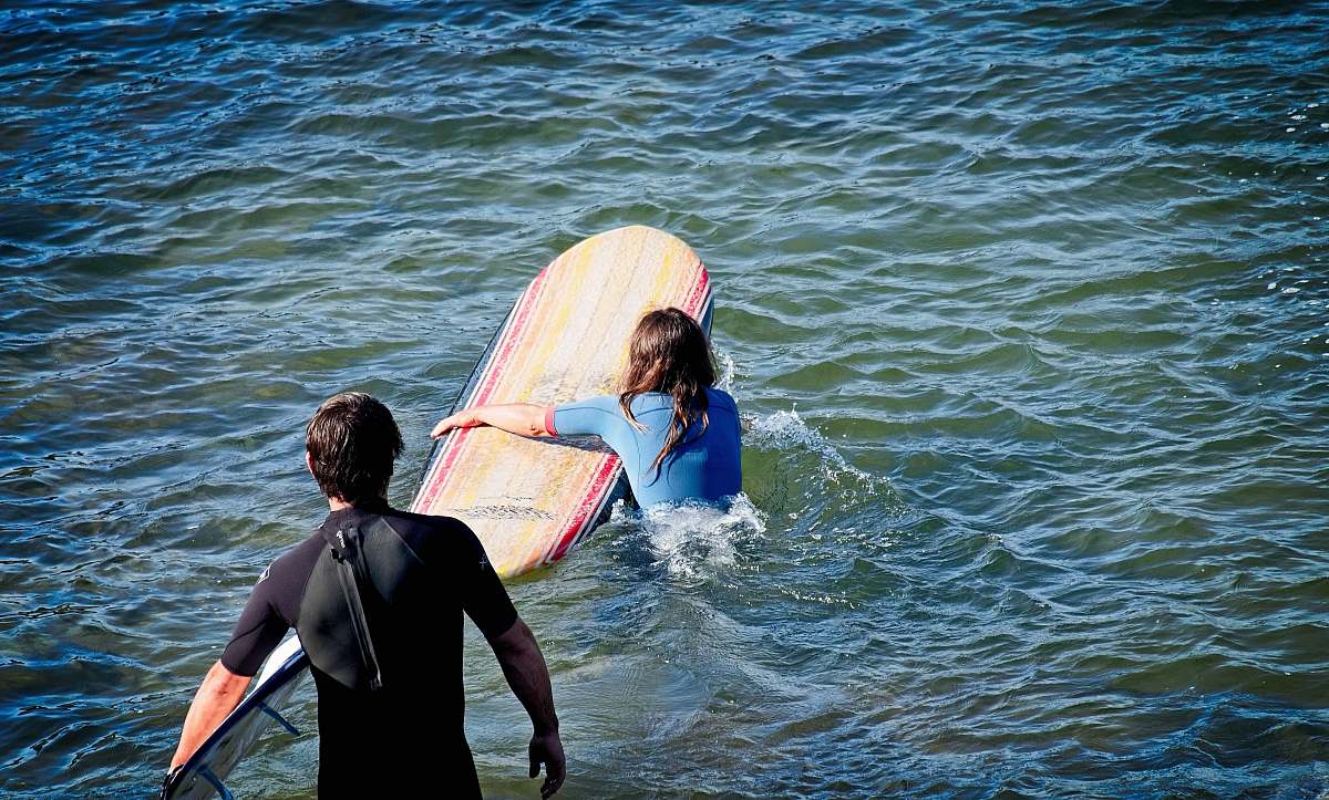 ocean woman holding surfboard near man standing on body of water sea