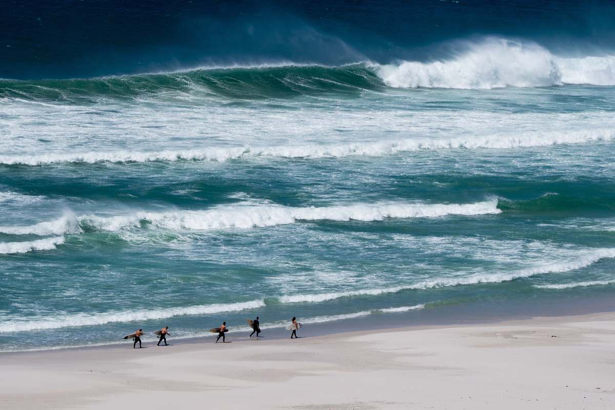 sea people carrying surfboard in seashore water