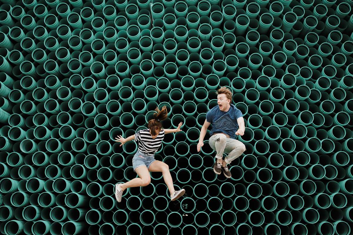 pattern minimalist photography of man and woman jumping in front of tube wall siloam springs