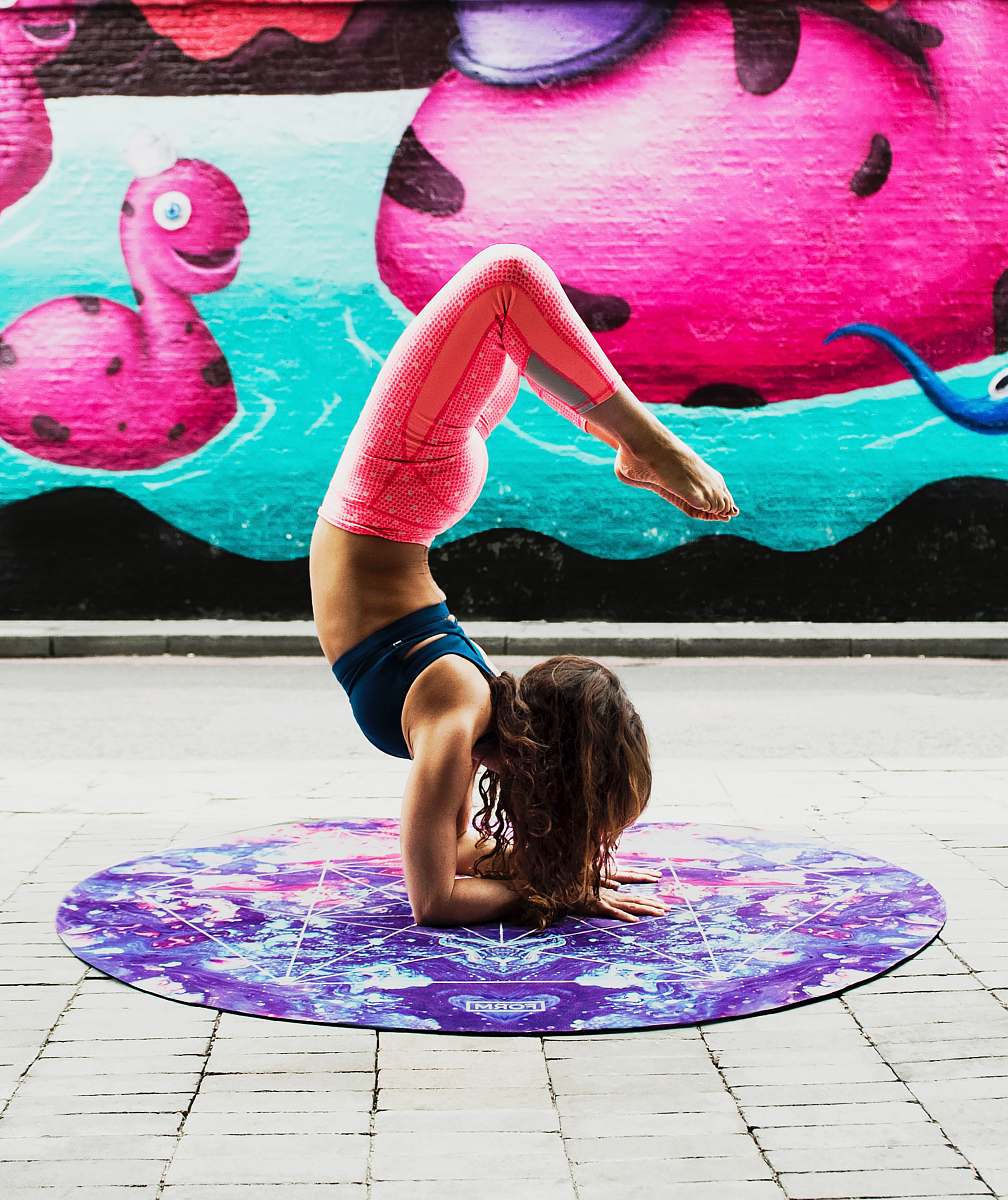 yoga woman doing acrobats on purple mat during daytime fitness