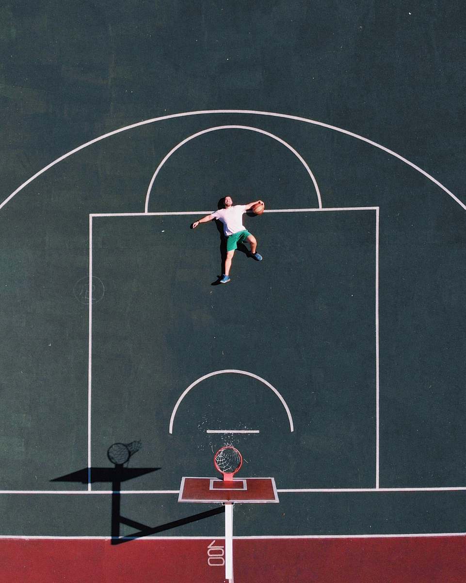 human aerial photography of man lying on basketball court people