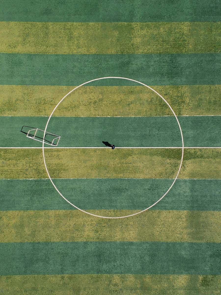 sport aerial view of person standing between circle field during daytime football field