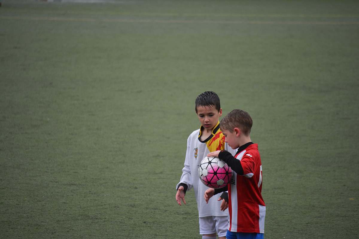 team boy holding soccer ball beside other ball on soccer field soccer