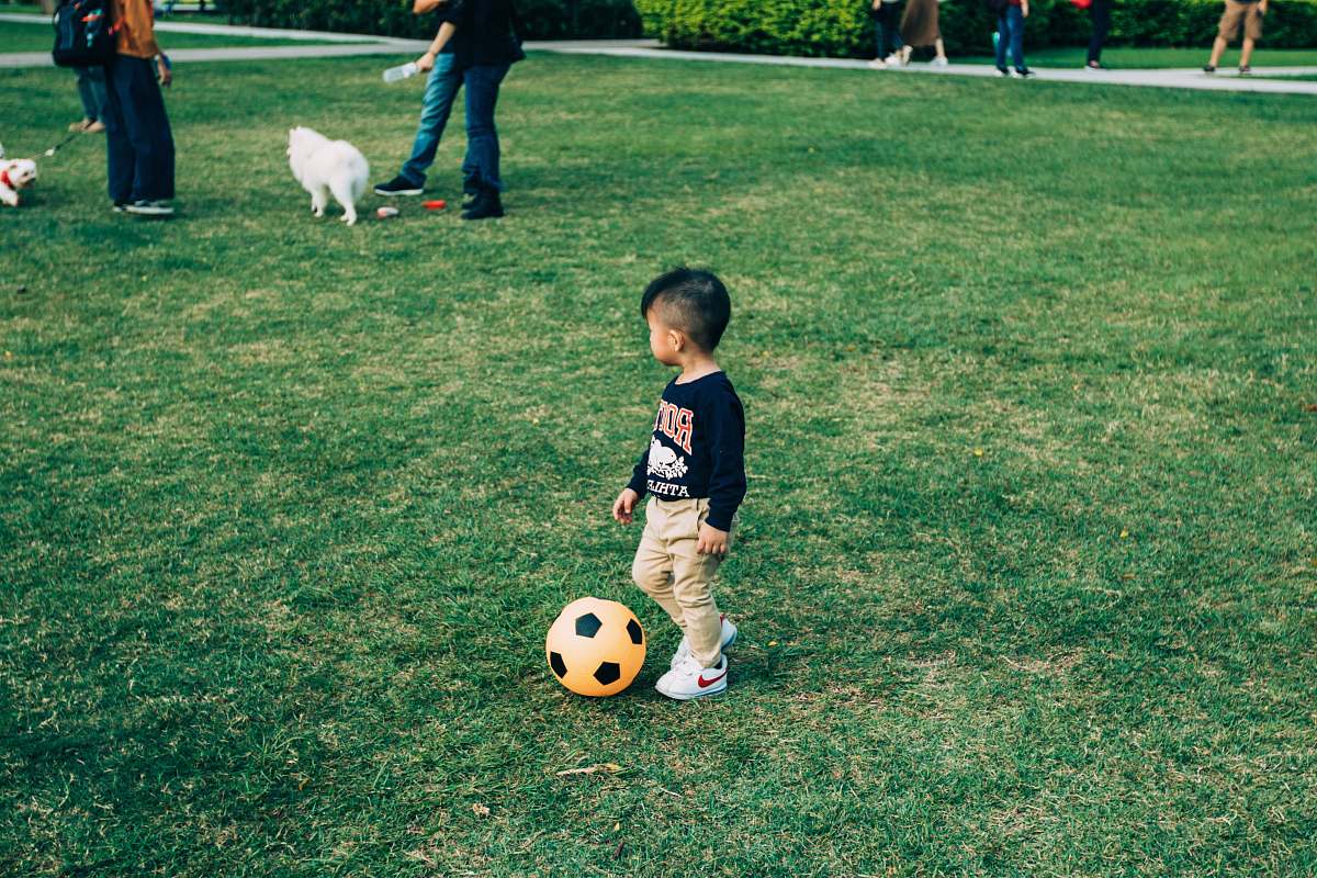human boy playing soccer on grass field ball