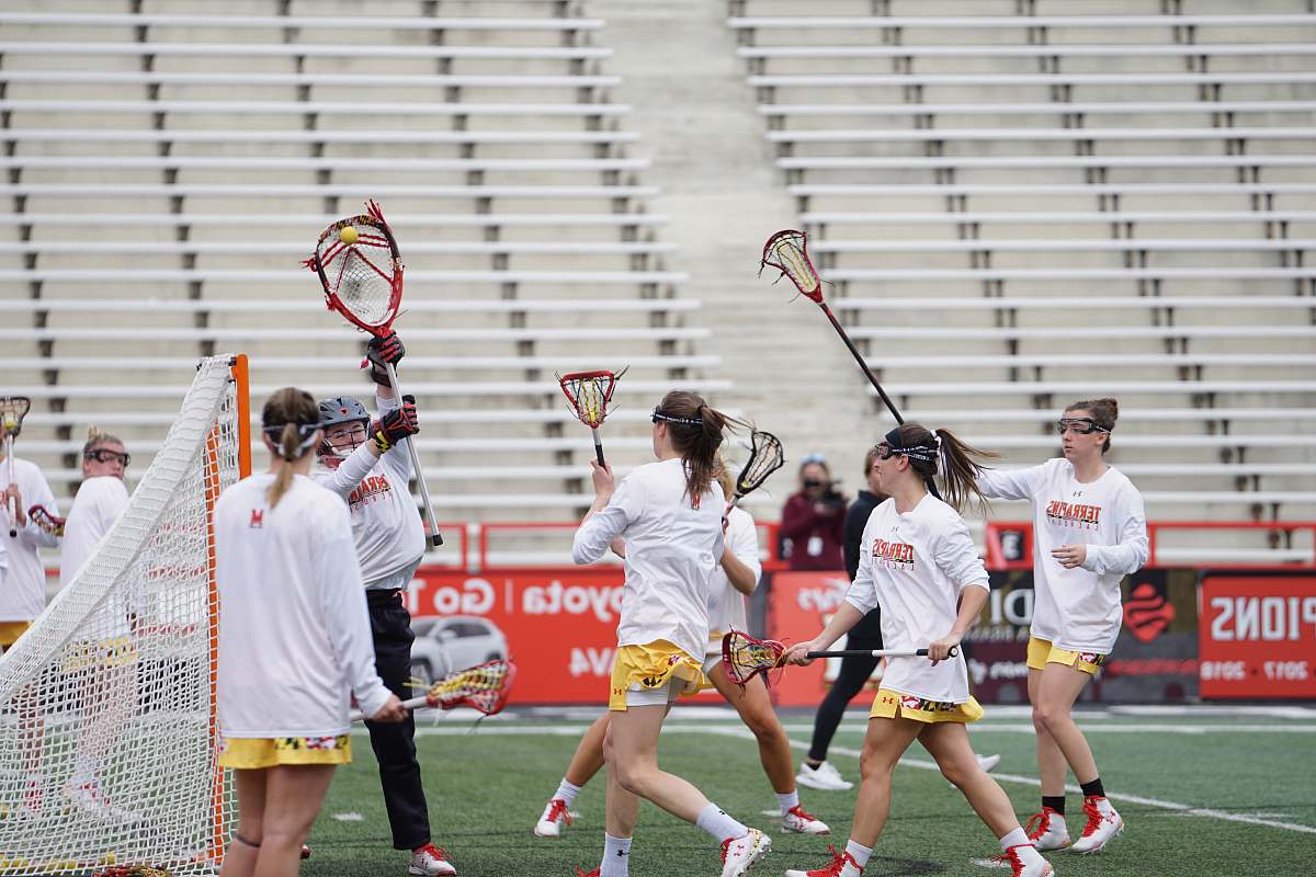 human group of people playing lacrosse on field apparel
