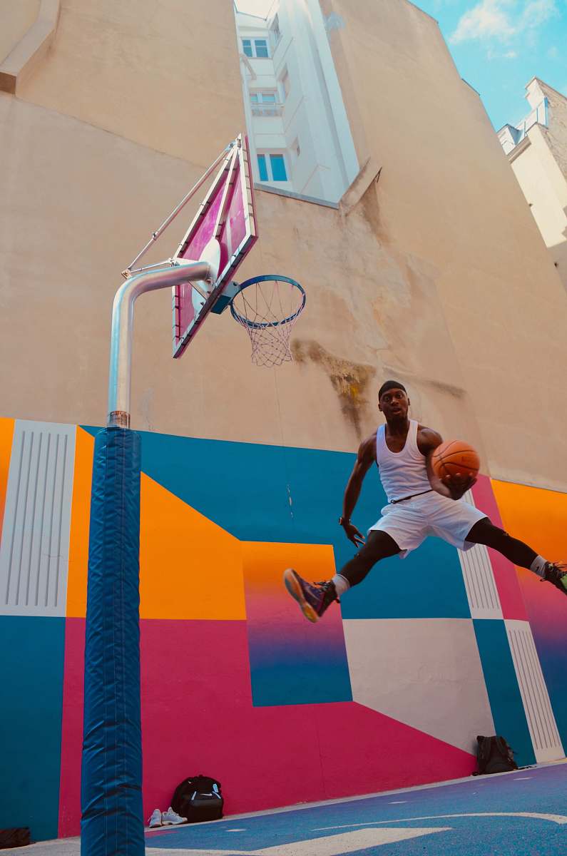 human man holding basket ball near concrete building people
