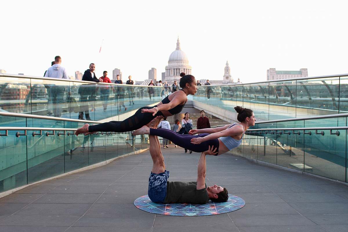 human man on his back supporting two women during daytime people
