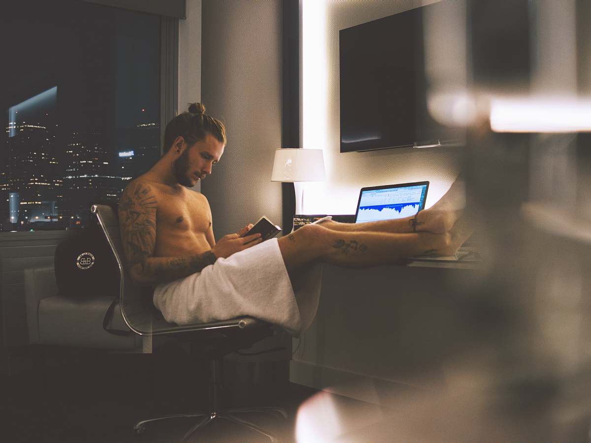 human man sitting on rolling chair while using smartphone laptop