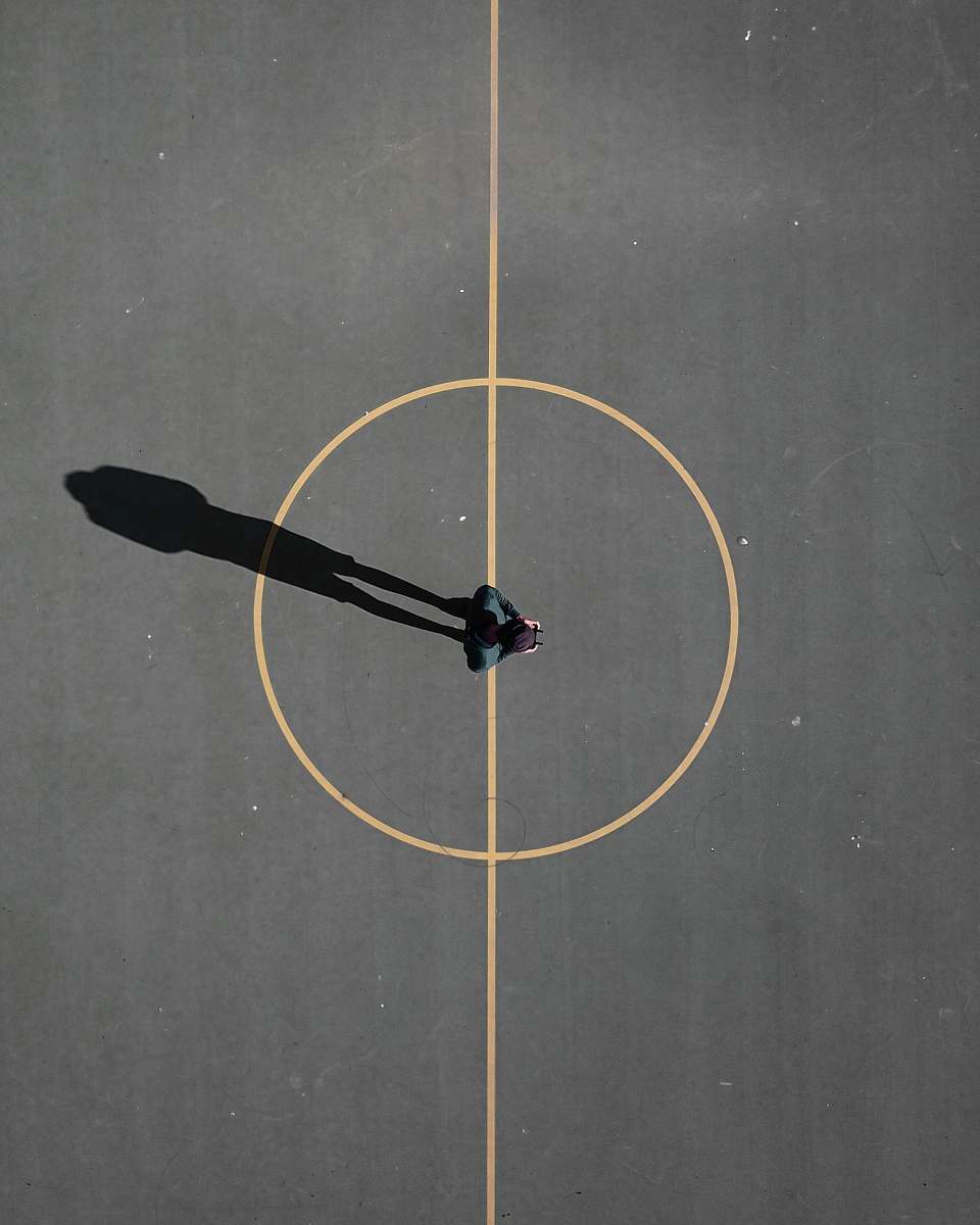 people man stainding on black concrete floor casting shadow basketball