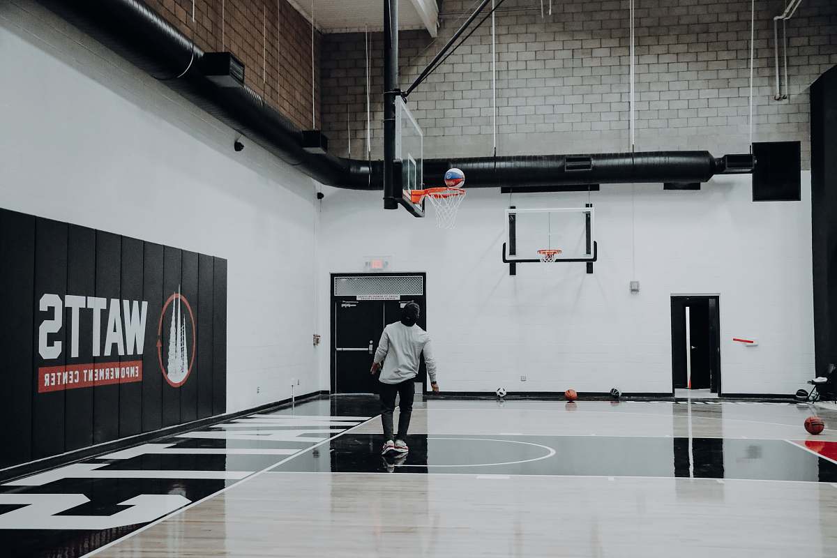 people man standing inside basketball court looking at ball on basketball hoop human