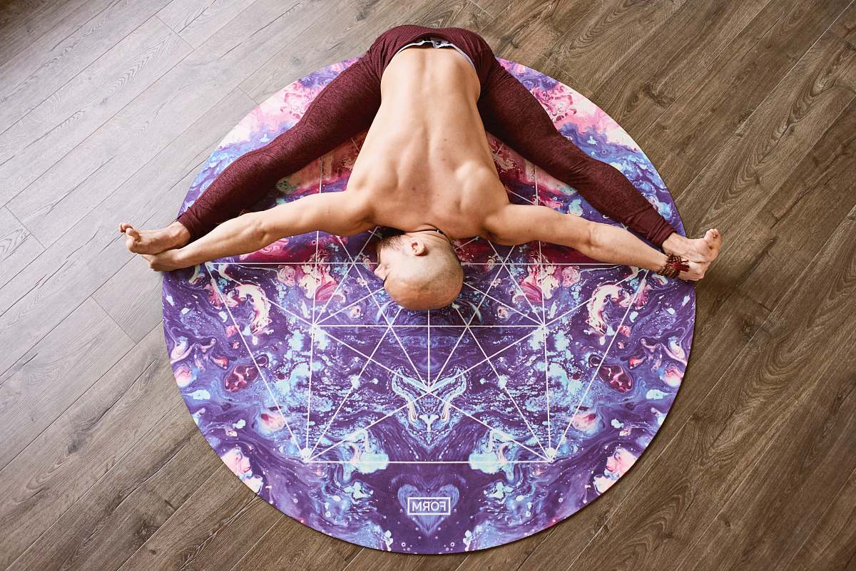 human man stretching on round purple mat on floor wood