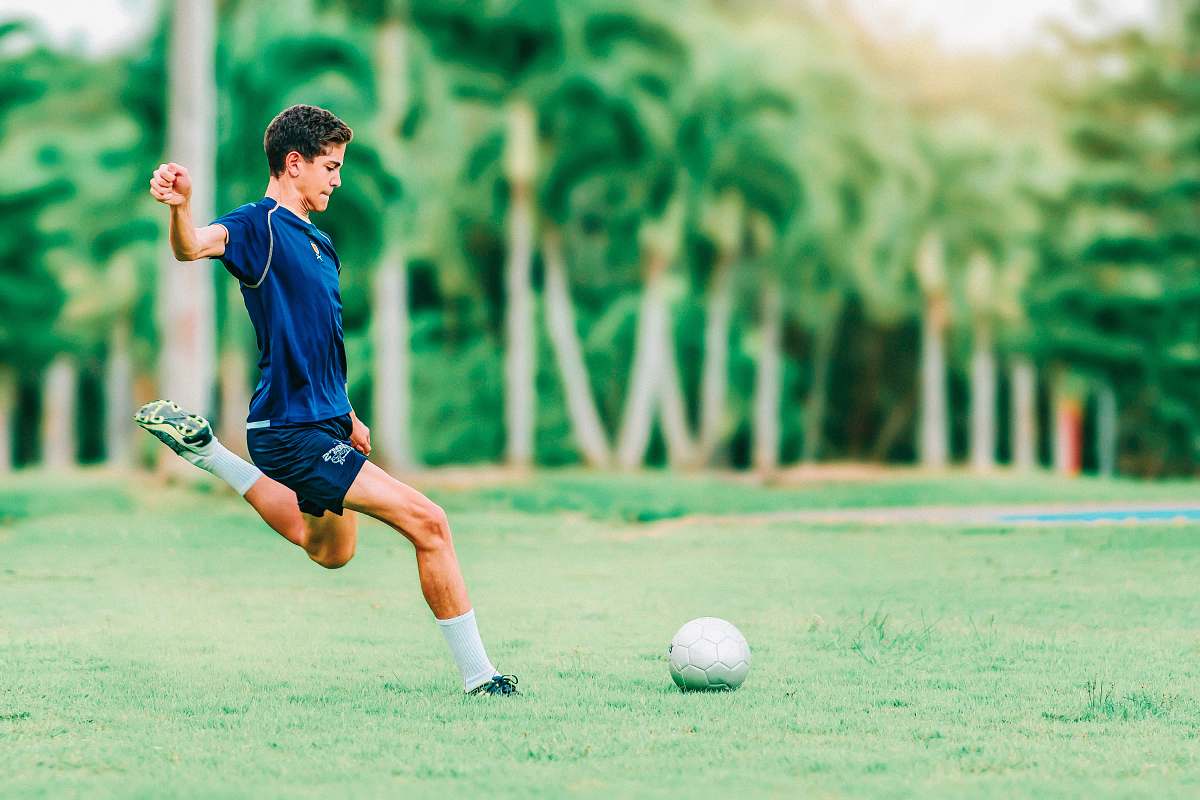 human man trying to kick soccer ball apparel