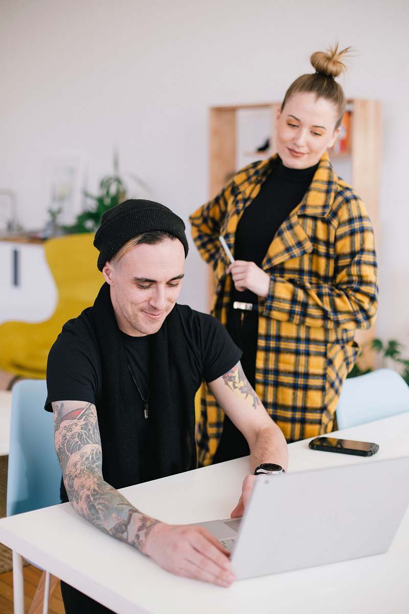 human man using laptop beside woman holding pen skin