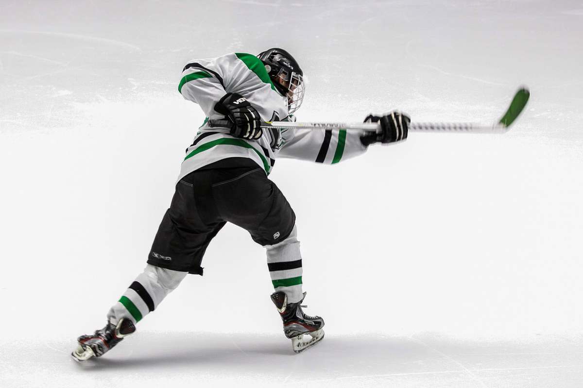 human man wearing green and white ice hockey jersey while playing helmet