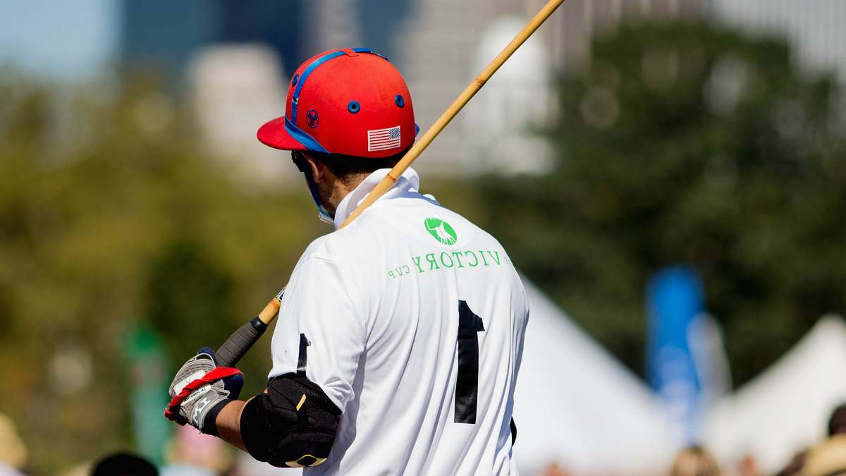 sport man wearing white and black 1 jersey shirt holding brown and black stick team