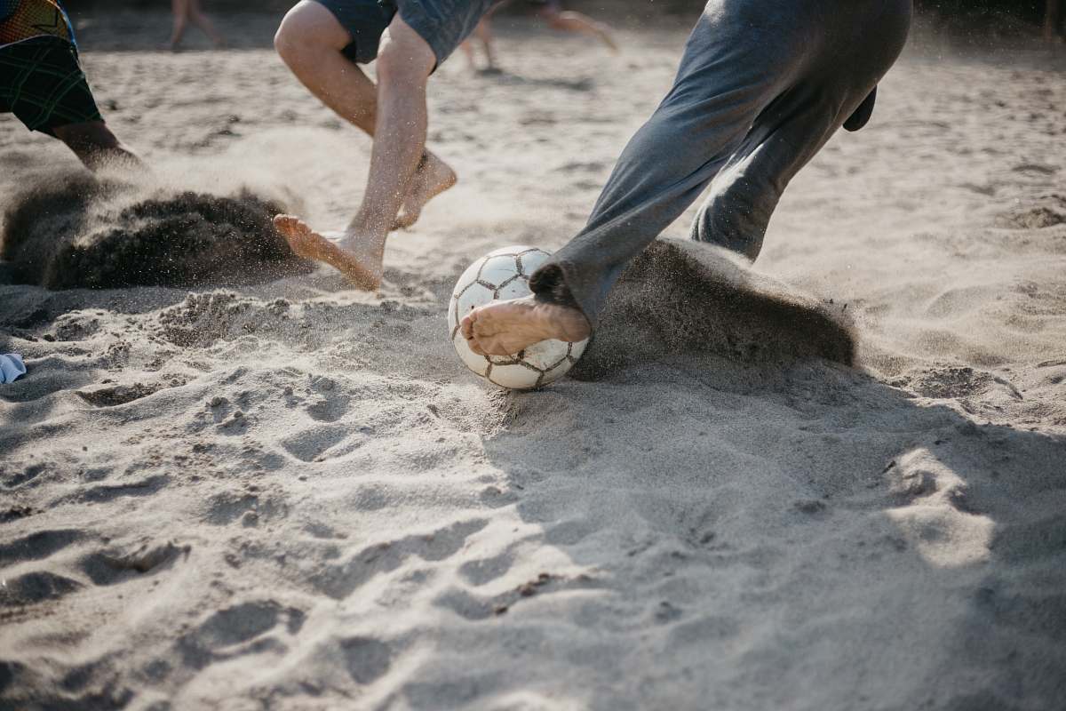 human people playing soccer on sand sphere
