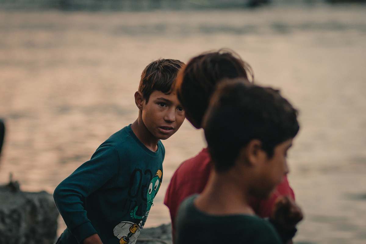 human three boys standing near body of water during daytime clothing