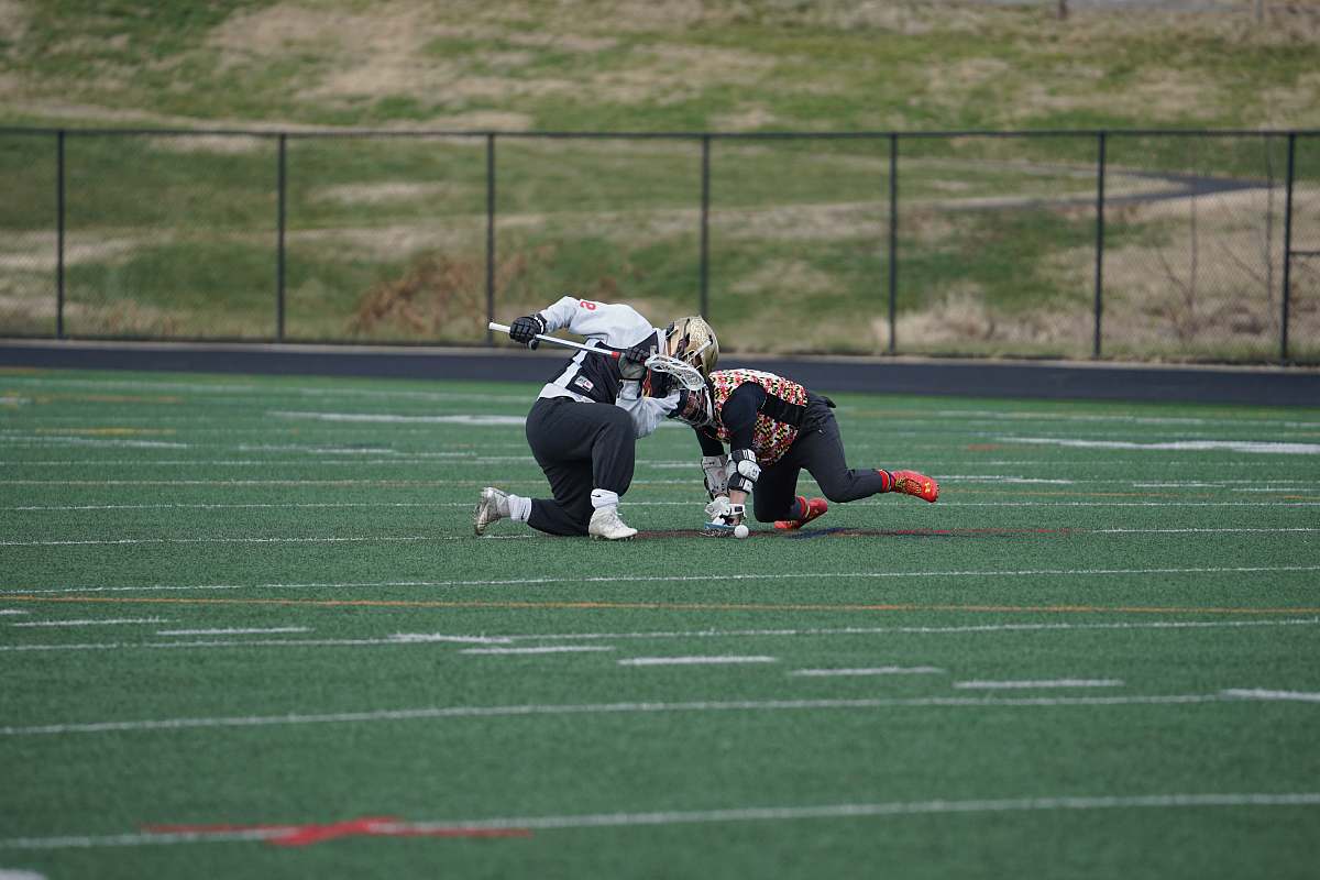 human two people playing lacrosse on green field people