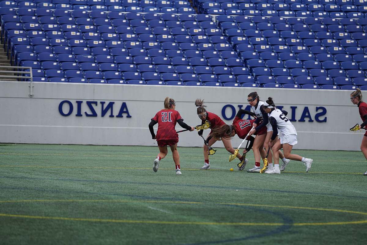 human women playing lacrosse on field people