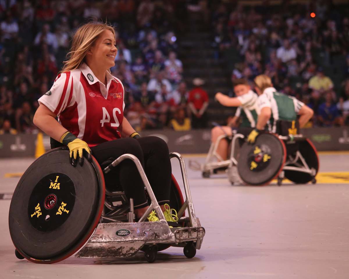 sports focus photo of woman in red and white polo shirt with black pants in ice wheelchair wheelchair