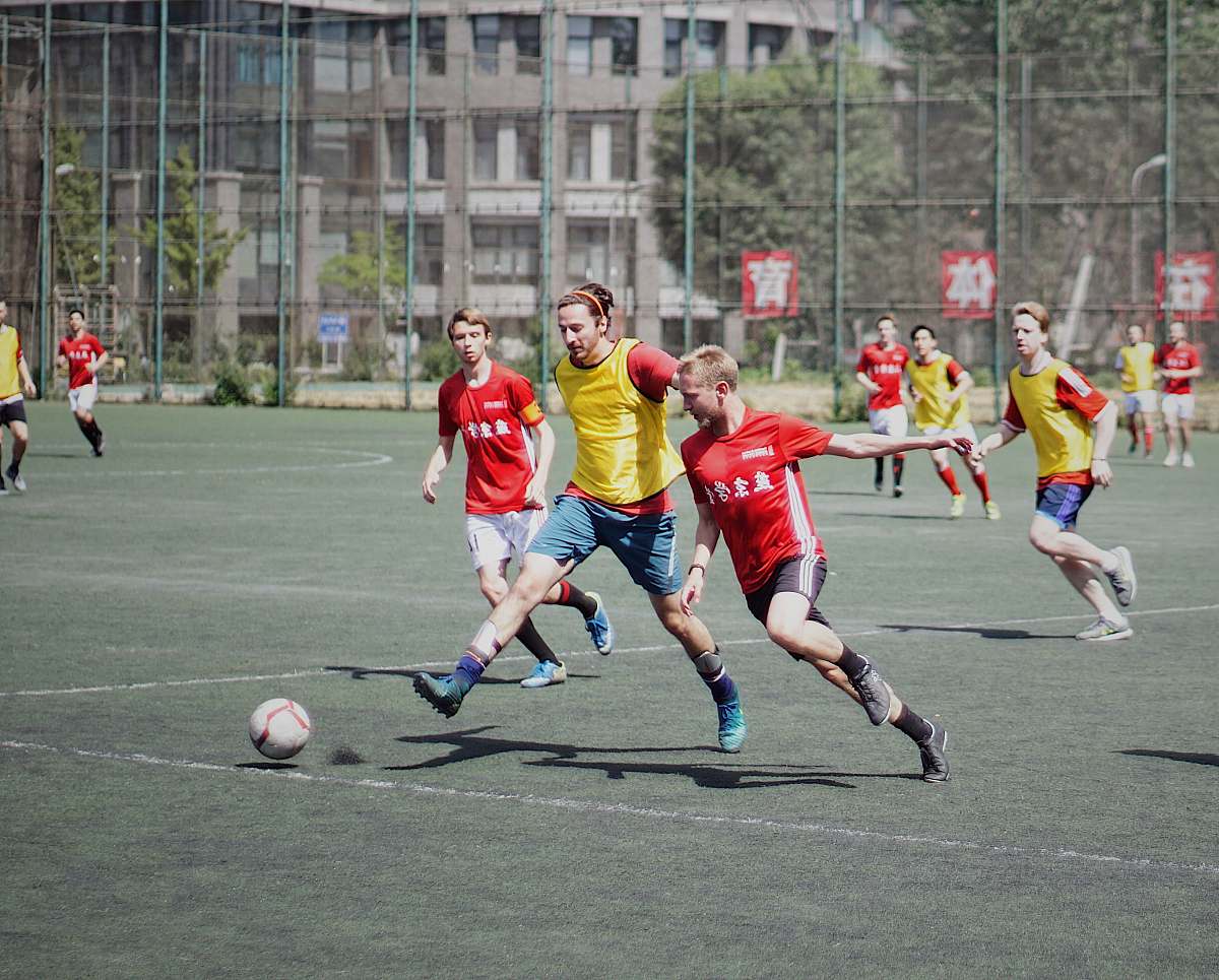 football men playing soccer on field with fence team