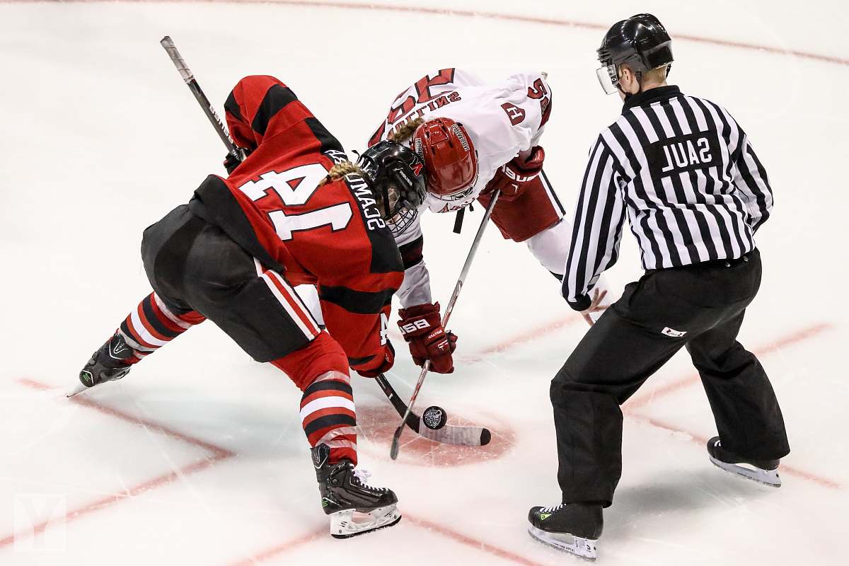 person two persons playing ice hockey with referee hockey