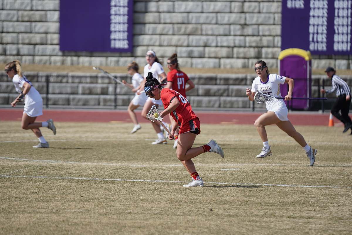 human women playing lacrosse at the open field person