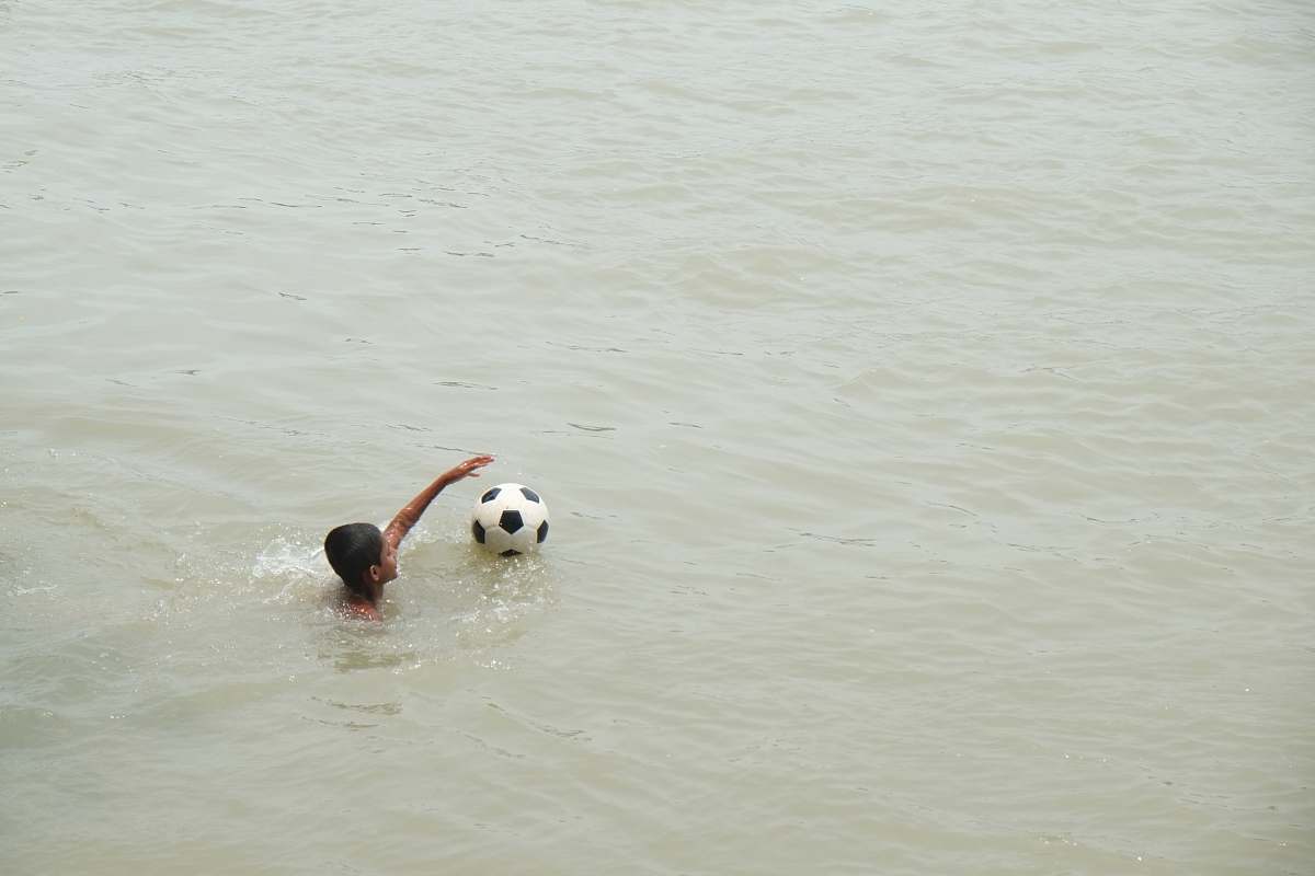 swimming boy playing on body of water with ball sports