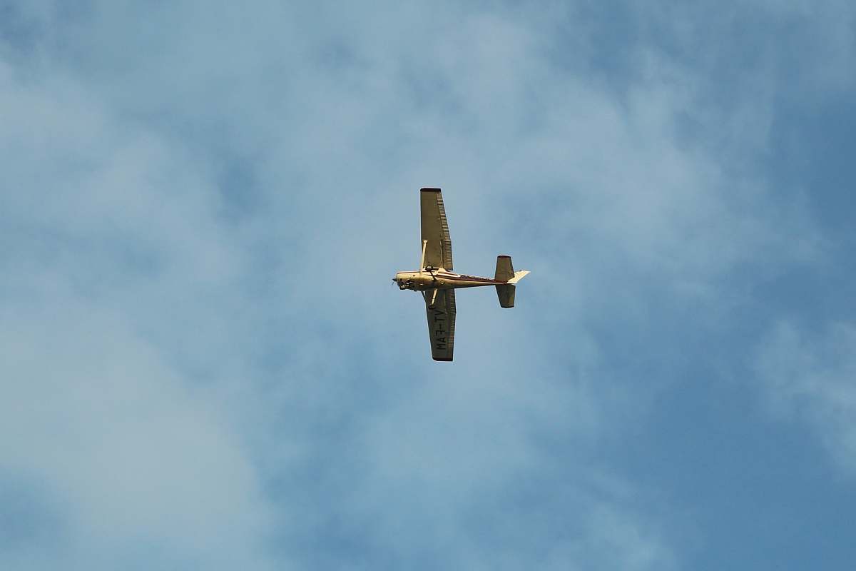 bird brown airplane flying under white clouds flying