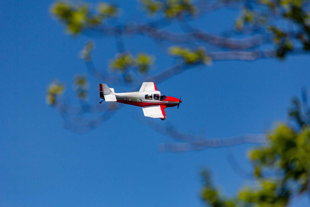 bird photography of white and red biplane during flight during daytime flying