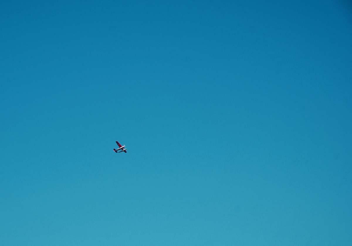 flying white plane under blue sky during daytime blue