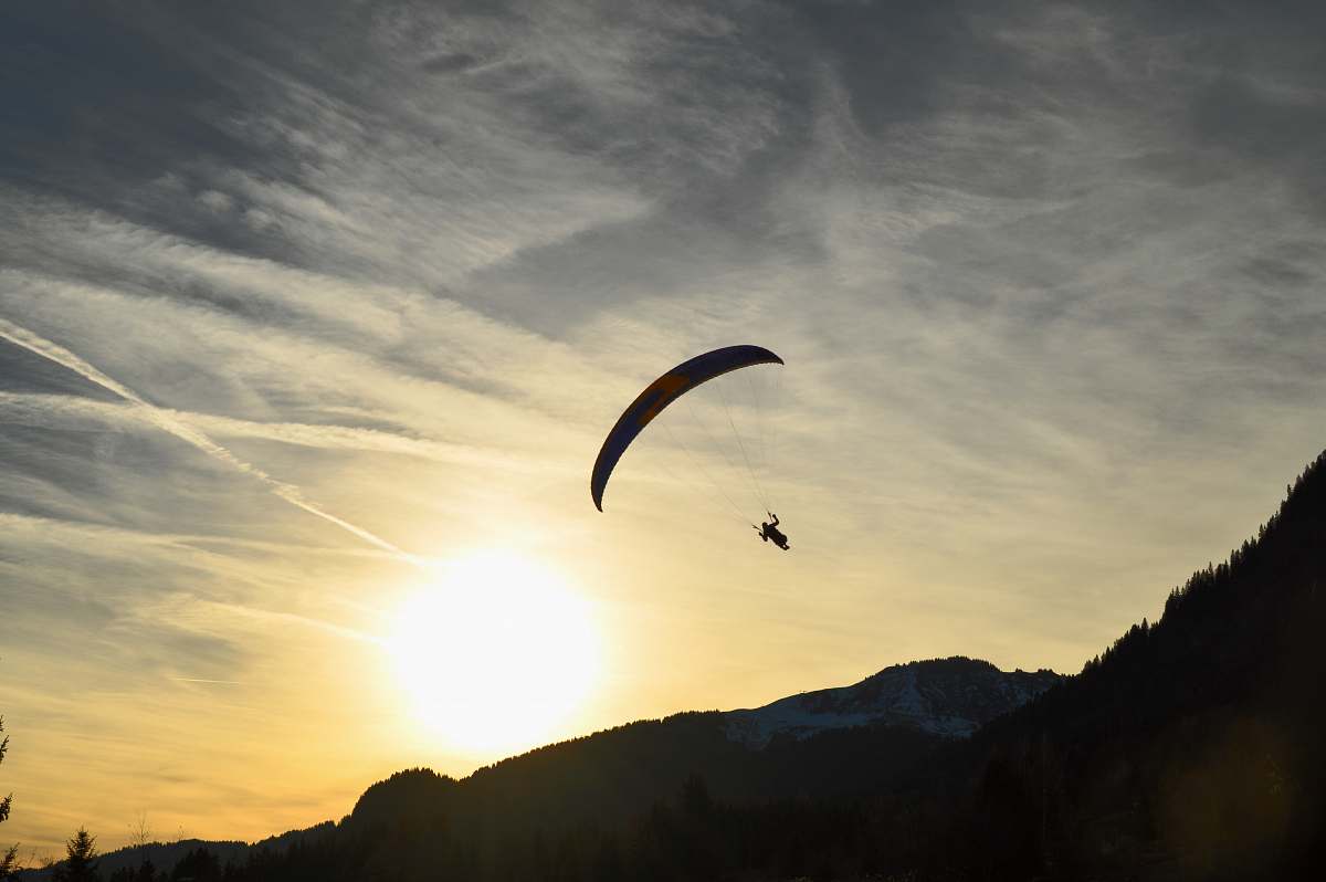 gliding silhouette of person parachuting during sunrise leisure activities